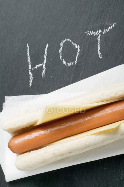 Hot dog with cheese on paper napkin — Stock Photo