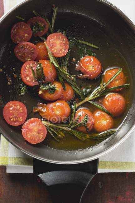 Жареные помидоры черри с розмарином в сковороде — стоковое фото