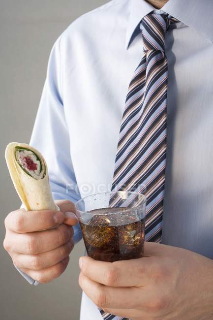 Крупный план человека в рубашке и галстуке с оберткой и колой — стоковое фото