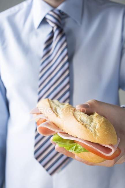 Homme d'affaires tenant sandwich jambon — Photo de stock
