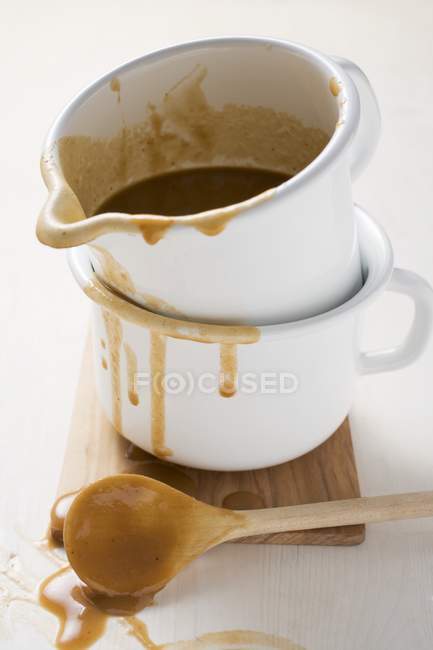 Closeup view of gravy in an enamel jugs by wooden spoon — Stock Photo