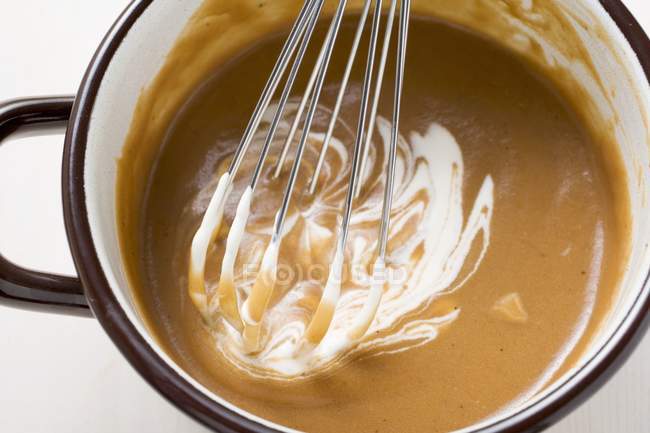 Closeup top view of stirring Creme fraiche with whisk in pot — Stock Photo