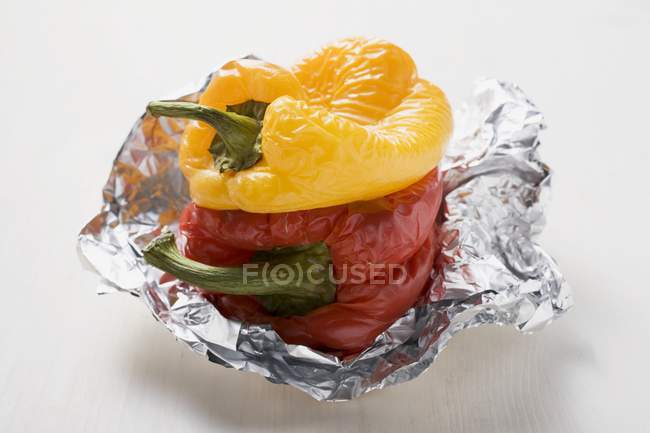 Grilled peppers on aluminium foil on white surface — Stock Photo