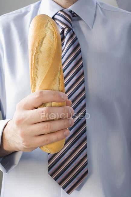Man wearing tie holding baguette — Stock Photo