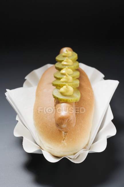 Hot dog with gherkins and mustard — Stock Photo