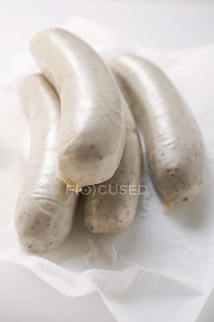 Fresh sausages on paper — Stock Photo
