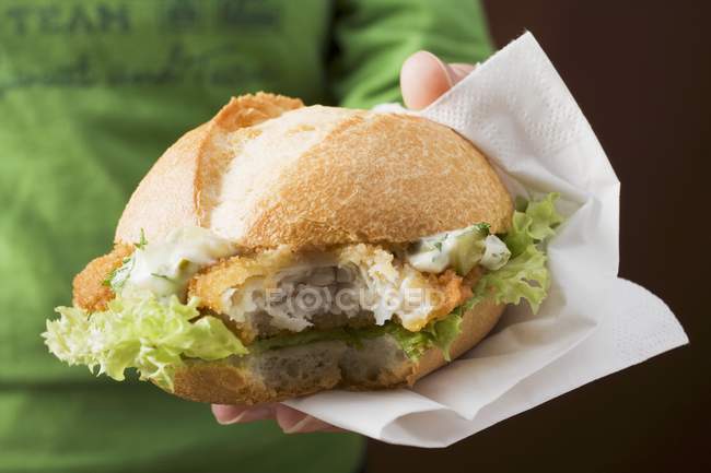 Closeup view of person holding a breaded escalope in a bread roll — Stock Photo