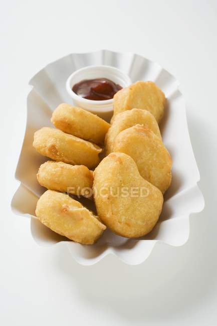 Closeup view of chicken nuggets with dip in paper dish — Stock Photo