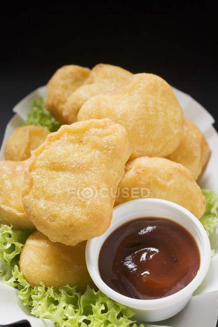 Closeup view of chicken nuggets with dip on lettuce leaves — Stock Photo