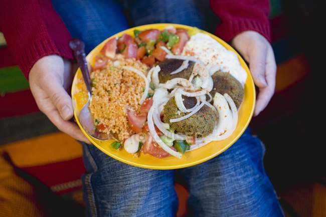 Person holding falafel with different accompaniments — Stock Photo