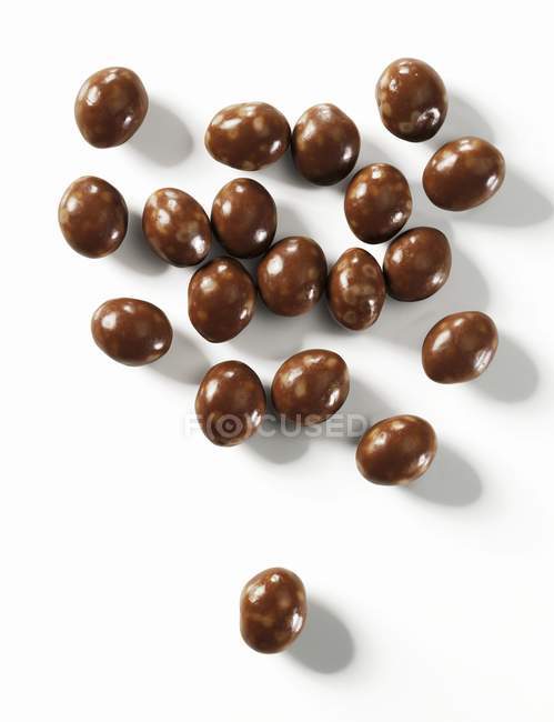 Closeup view of chocolate beans on white surface — Stock Photo