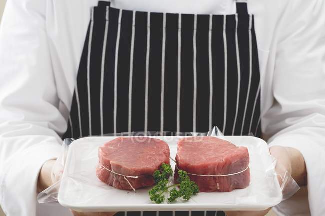 Chef sosteniendo carne de res envuelta en tocino - foto de stock