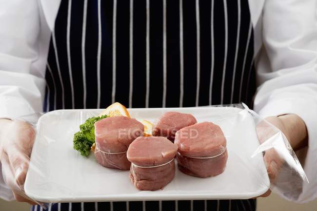 Koch hält Tablett mit Schweinemedaillons in der Hand — Stockfoto