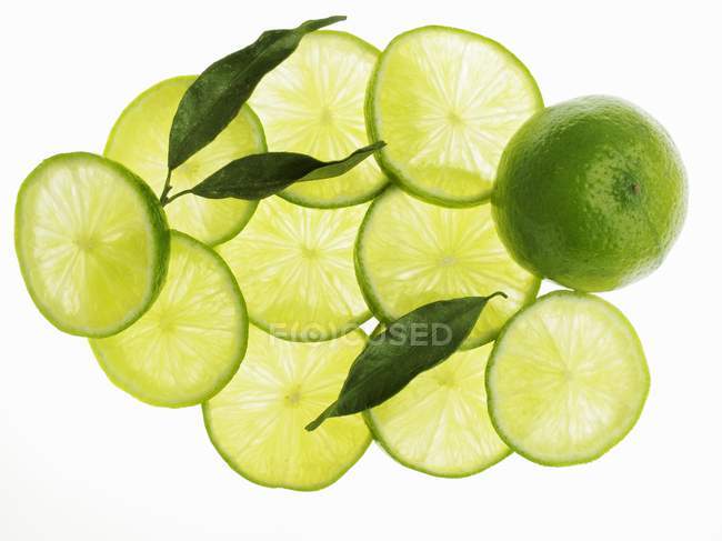 Limes entières et tranchées aux feuilles — Photo de stock