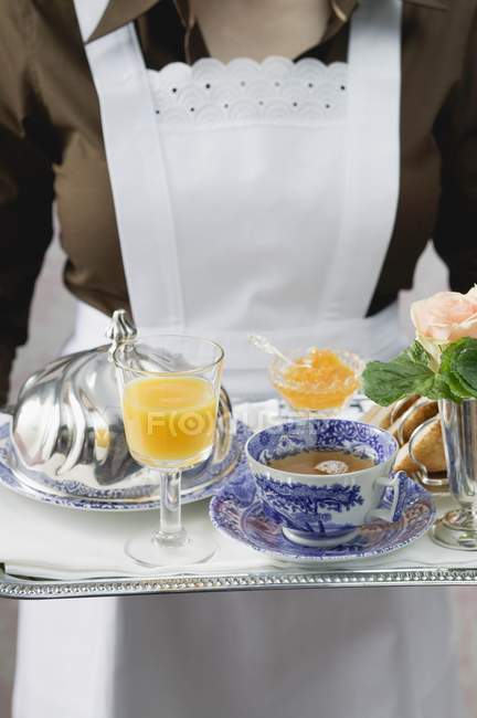 Vista ritagliata della cameriera che serve vassoio per la colazione con caffè e succo di frutta — Foto stock