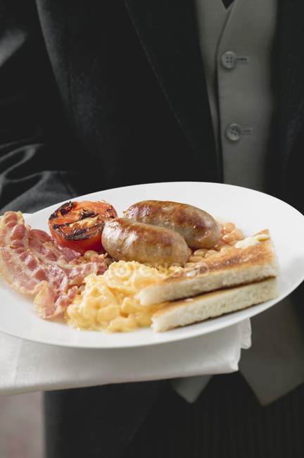 Butler que serve pequeno-almoço inglês no prato — Fotografia de Stock