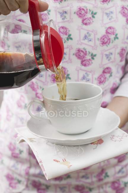 Frau gießt Kaffee in Tasse — Stockfoto