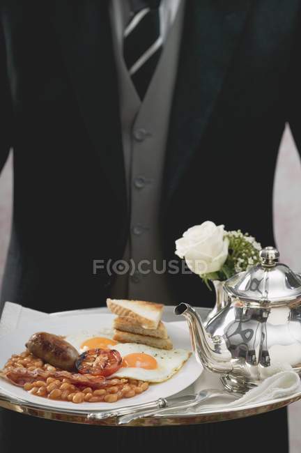 Maggiordomo che serve colazione inglese su vassoio — Foto stock