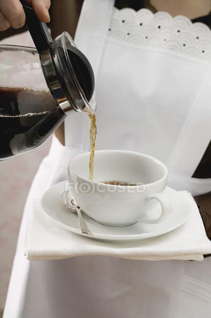 Zimmermädchen gießt Kaffee in Tasse — Stockfoto