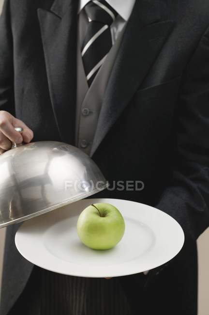 Butler serving apple on plate — Stock Photo