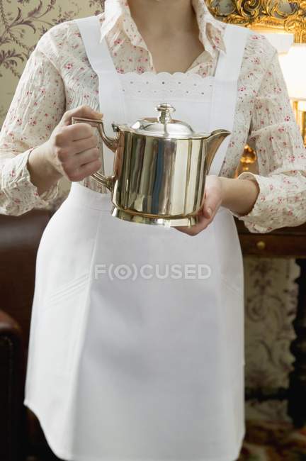 Cropped view of chambermaid holding silver pot — Stock Photo