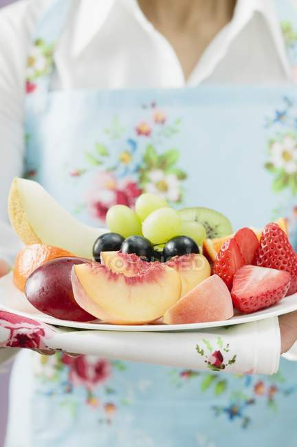 Closeup cropped view of woman holding plate of fresh fruit — Stock Photo