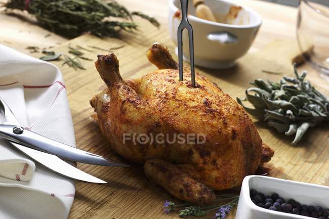 Vista de cerca de pollo asado con tenedor, tijeras y hierbas - foto de stock