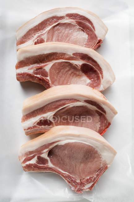 Chuletas de cerdo crudas en fila - foto de stock