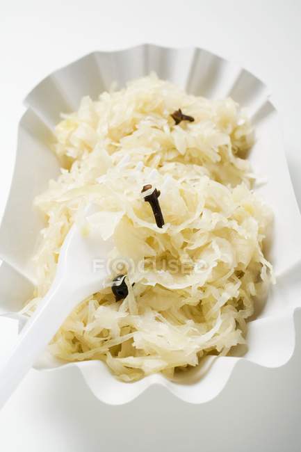 Sauerkraut in Papierschüssel mit Plastikgabel auf weißem Hintergrund — Stockfoto