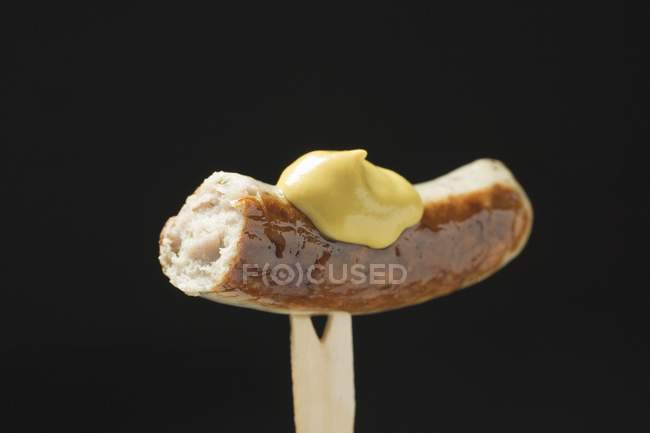 Salchicha con mostaza sobre tenedor de madera - foto de stock