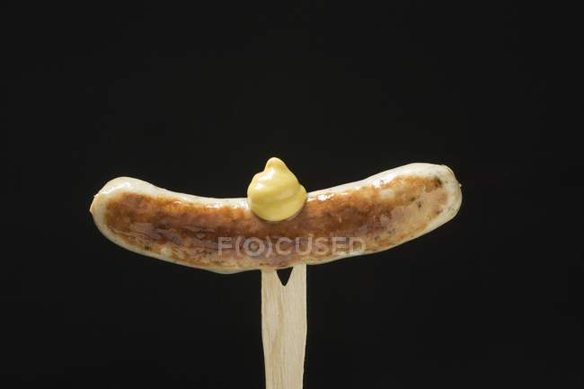 Sausage with mustard on wooden fork — Stock Photo