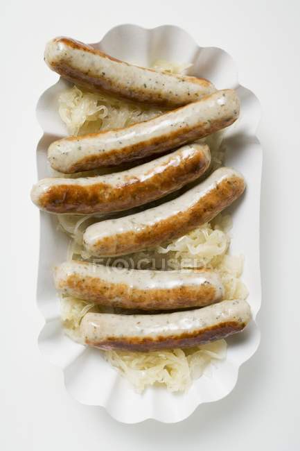 Колбасы с квашеной капустой на бумажной тарелке — стоковое фото