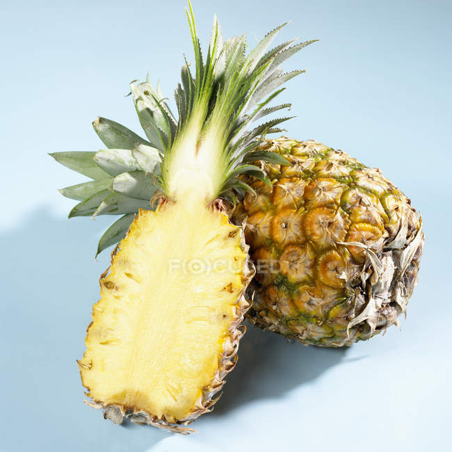 Halved and whole pineapples — Stock Photo