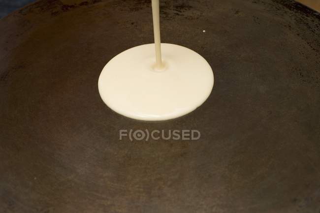 Closeup view of pouring raw crepe mixture on hot plate — Stock Photo