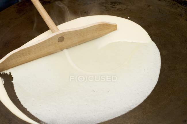 Closeup view of spreading mixture for crepe on hotplate — Stock Photo
