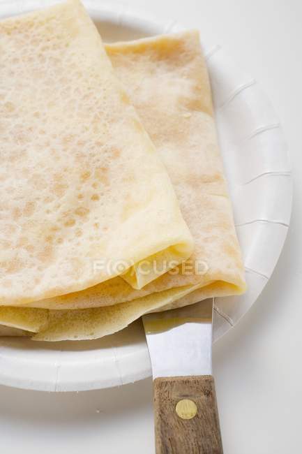 Closeup view of crepes and spatula on paper plate — Stock Photo
