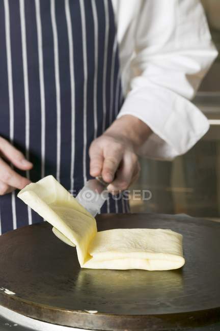 Vista cortada do cozinheiro dobrando um crepe na superfície de fritura — Fotografia de Stock
