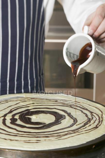 Nahaufnahme ausgeschnittene Ansicht einer Person, die Schokolade auf Crêpe gießt — Stockfoto