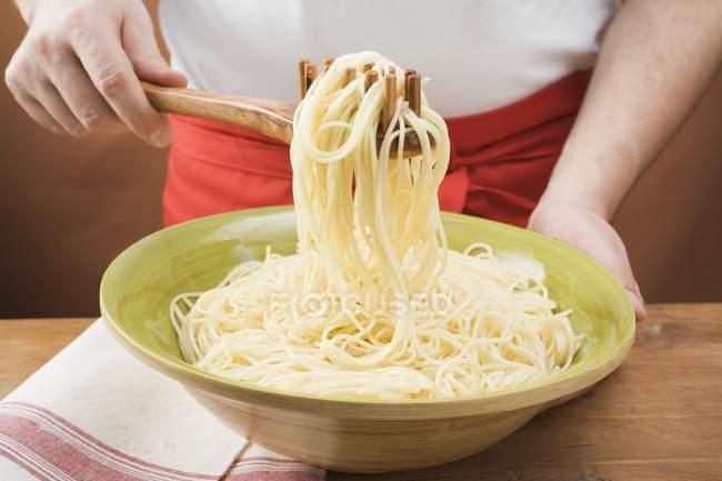Person picking up cooked spaghetti — Stock Photo