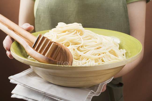 Woman holding bowl of cooked spaghetti — Stock Photo