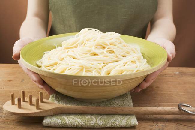 Woman holding bowl of cooked spaghetti — Stock Photo