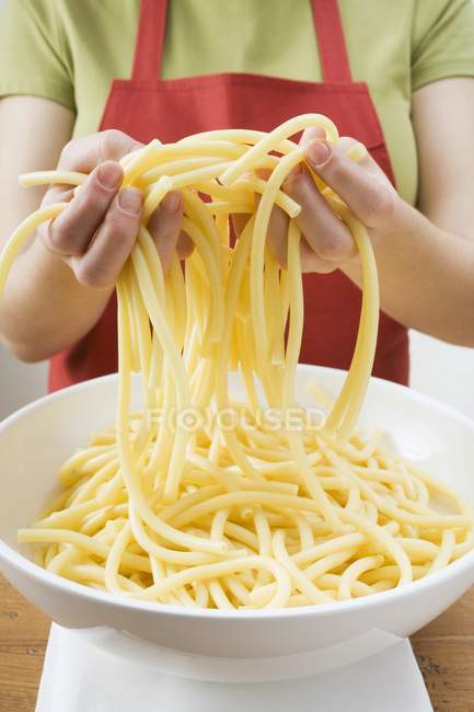 Woman lifting macaroni with hands — Stock Photo