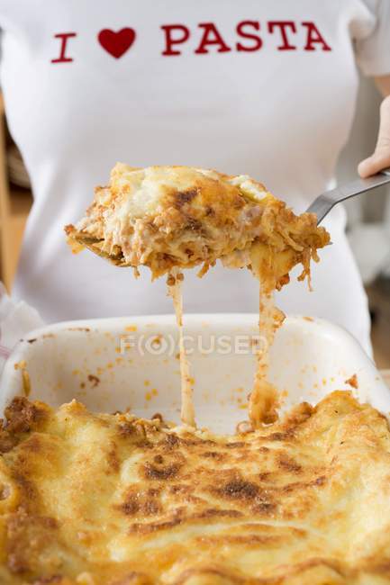 Frau nimmt Portion Lasagne — Stockfoto
