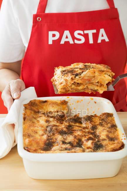 Frau nimmt Portion Lasagne — Stockfoto