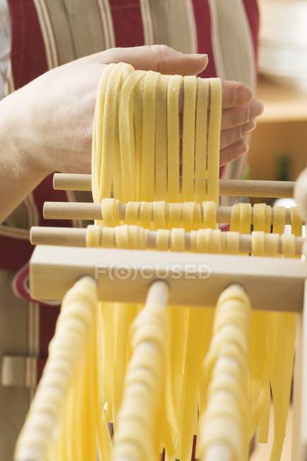 Woman hanging homemade ribbon pasta — Stock Photo