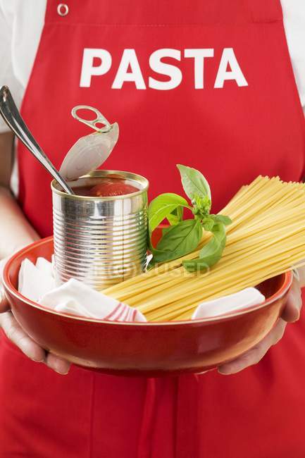 Женщина держит спагетти и банку помидоров — стоковое фото