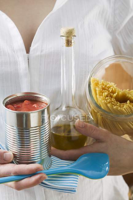Woman holding spaghetti and tin of tomatoes — Stock Photo