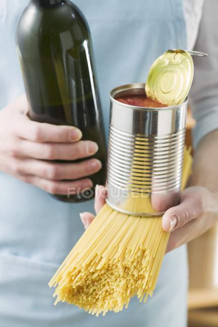 Женщина держит спагетти и банку помидоров — стоковое фото