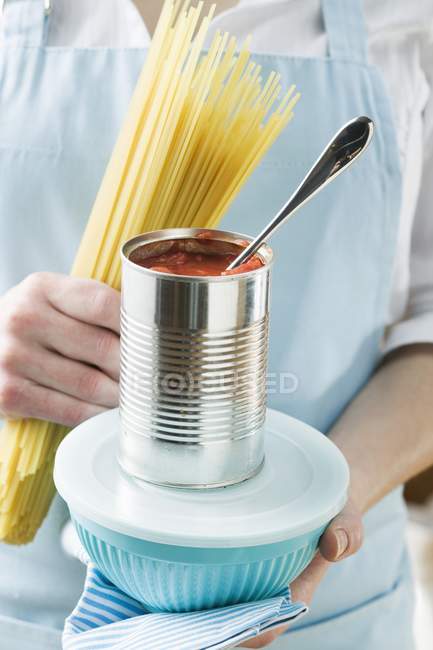 Woman holding spaghetti and tin of tomatoes — Stock Photo