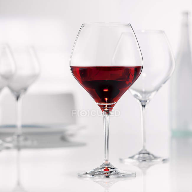 Burgunderglas mit leeren Gläsern — Stockfoto